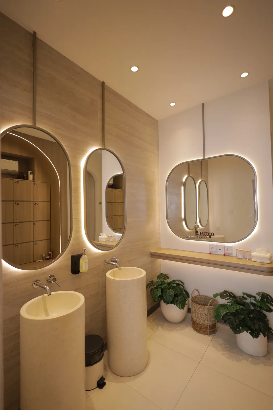 The washroom with arched backlit mirrors and a stone basin