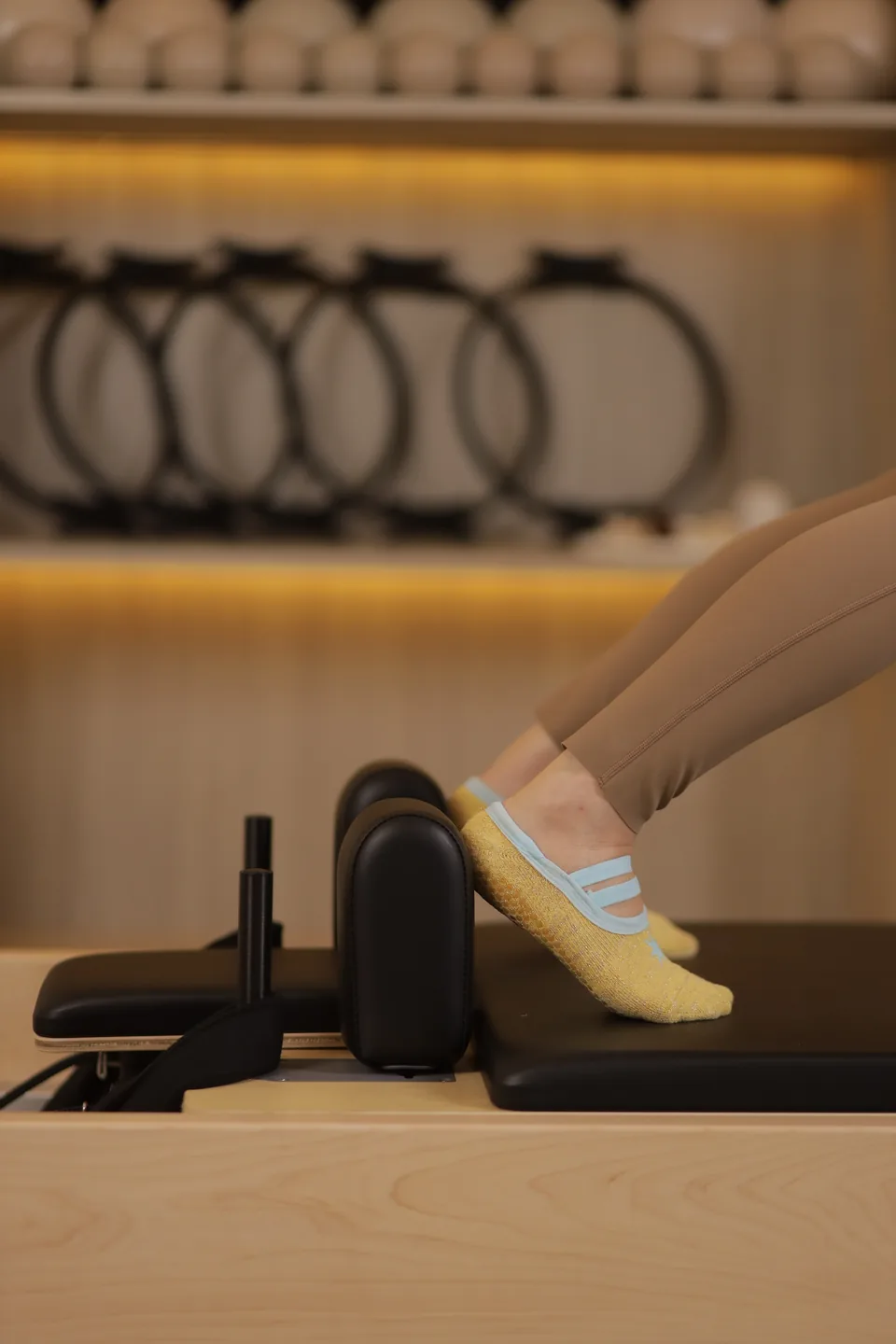 Grip socks resting on the reformer footbar, prop wall behind