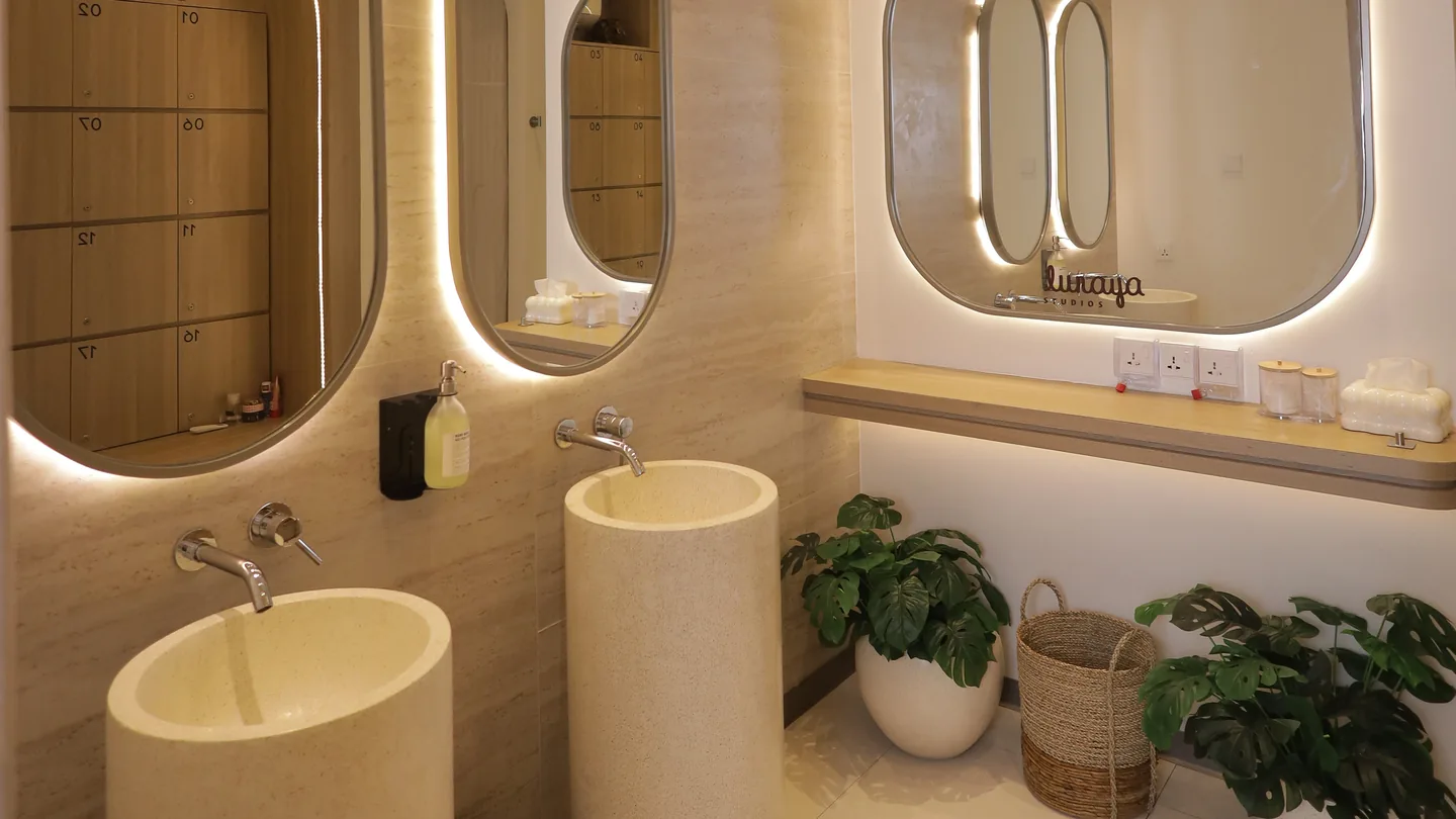 The washroom with arched backlit mirrors and a stone basin